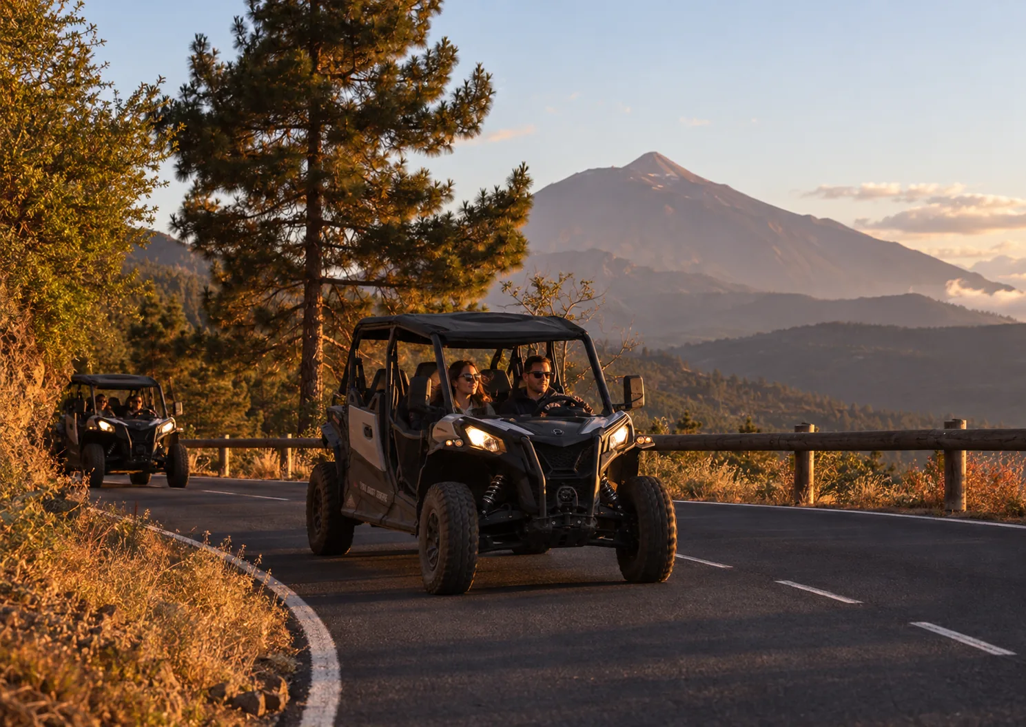 Buggies driving on a road at sunset with Mount Teide behind them
