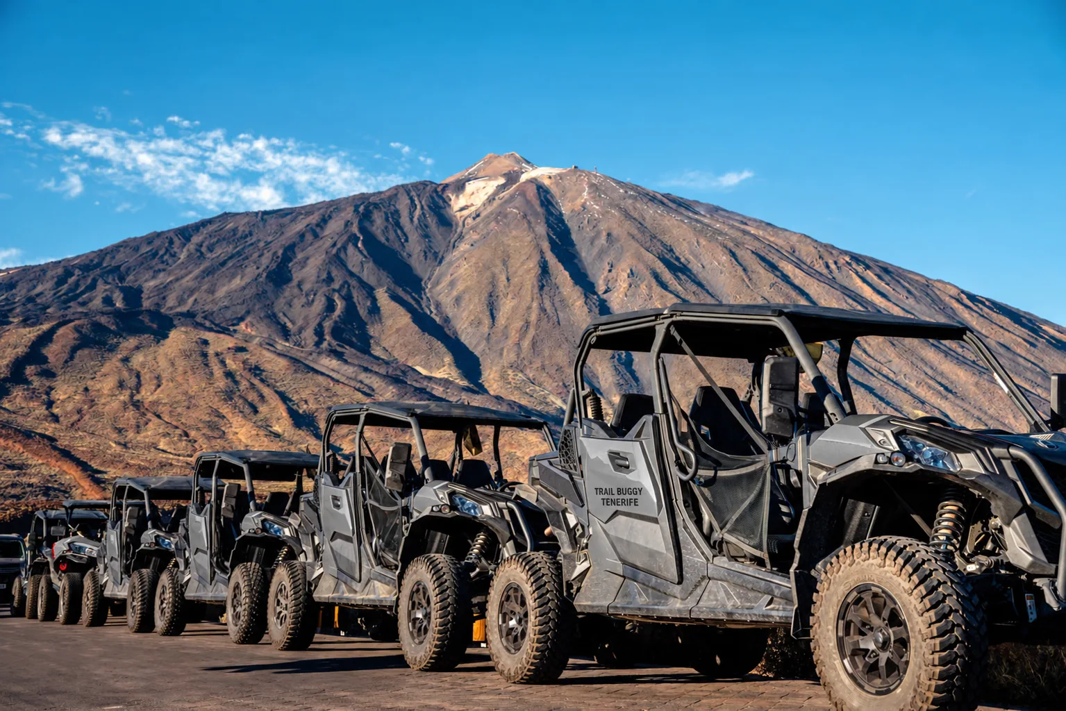 A line of buggies ready to set off with Mount Teide behind them, on a clear day