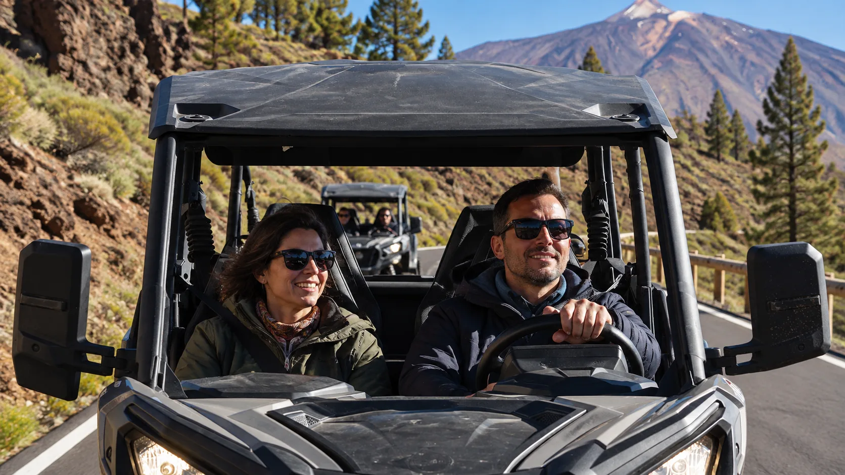 A couple driving a buggy on a road, with Mount Teide behind them